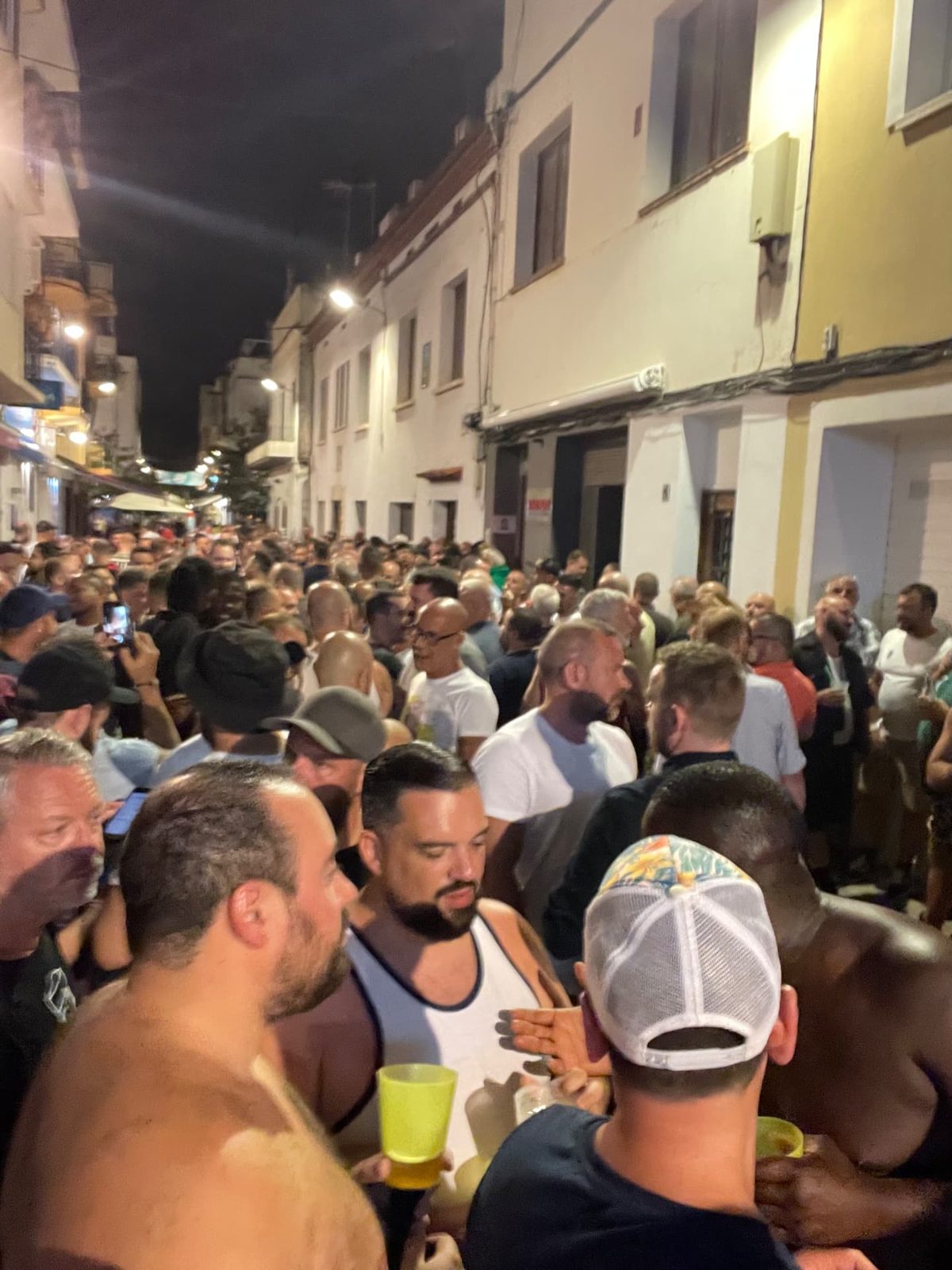 A narrow Sitges street packed with bears at night during Bear Week