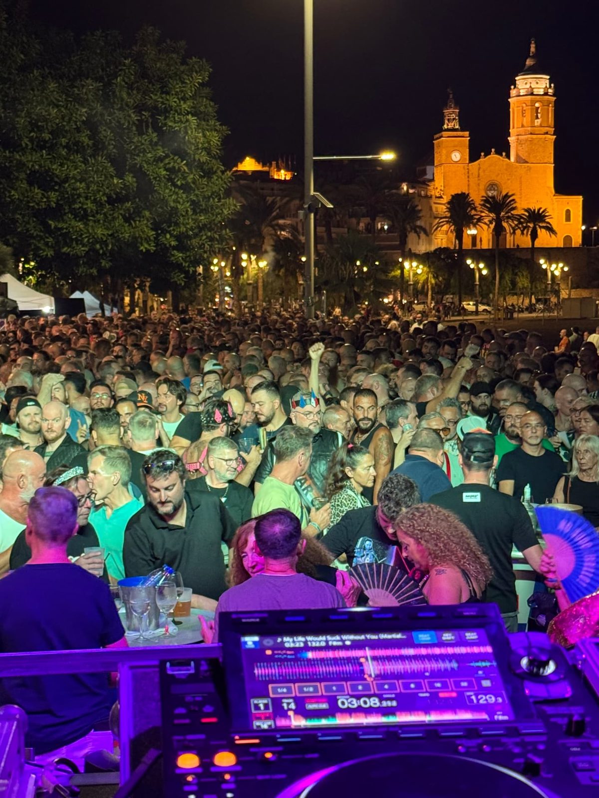 View from the DJ booth over the Bear Village crowd with the Sitges church lit up behind