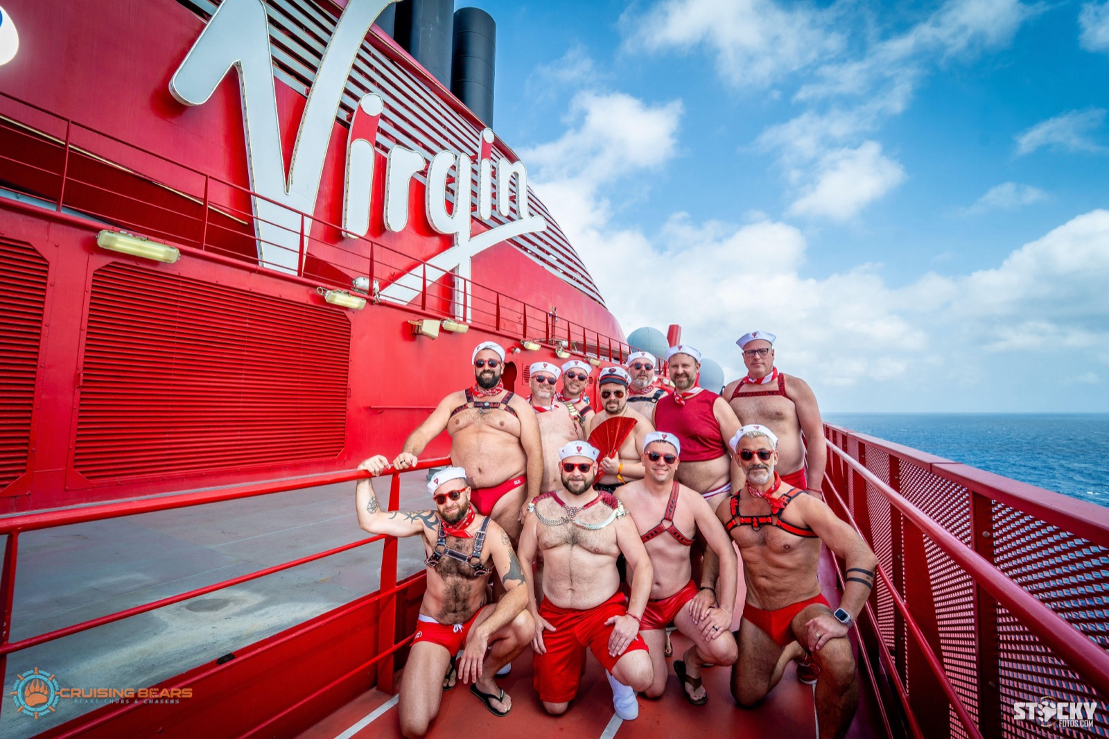 Crew group in sailor caps and harnesses on deck in front of the Virgin Voyages logo