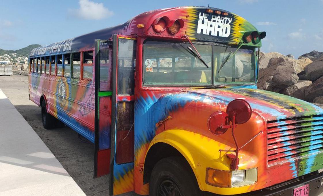 Tie-dye painted party bus in St. Kitts with “We Party Hard” lettering