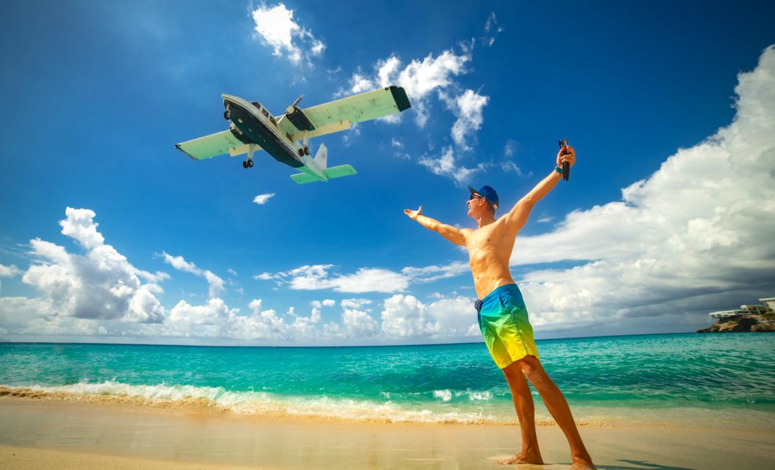 Traveler on Maho Beach in St. Maarten as a plane flies low overhead
