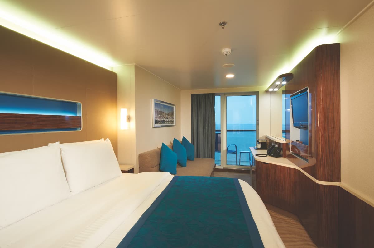 Norwegian balcony stateroom with king bed, sofa and private balcony overlooking the ocean
